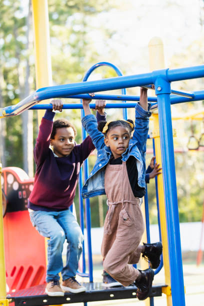 istock Mixed race girl playing with siblings on playground 1305651530