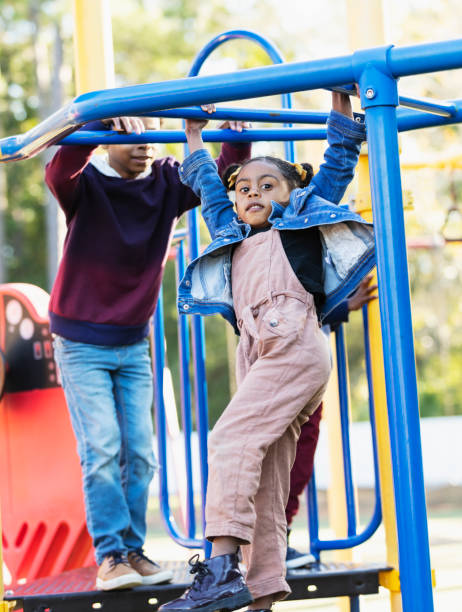 istock Mixed race girl playing with siblings on playground 1305651538