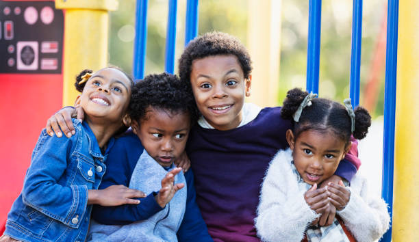 istock Four young siblings hugging on playground 1305651558