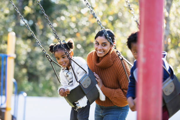 istock Mother with daughter on playground swing 1305651602