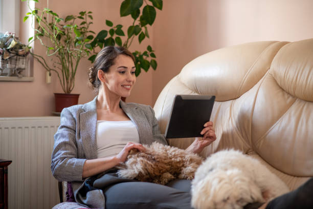 istock One young woman is using tablet while her two dogs are napping in her lap. 1305651630