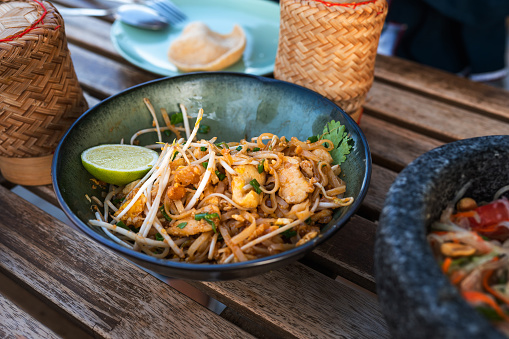 Thai food stir friend noodles Pad Thai with chicken in a bowl on a table closeup