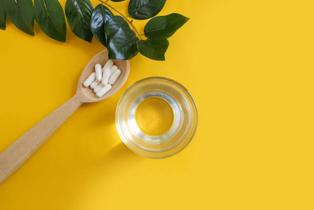 istock wooden spoon, collagen capsules on a colored background 1305656608