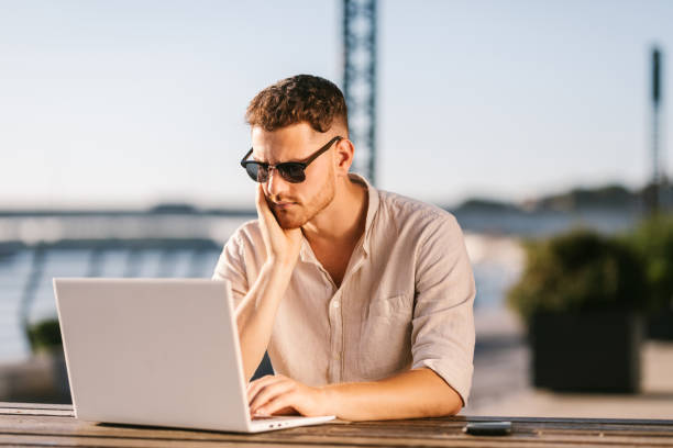 istock Young handsome man using laptop outdoors 1305659096