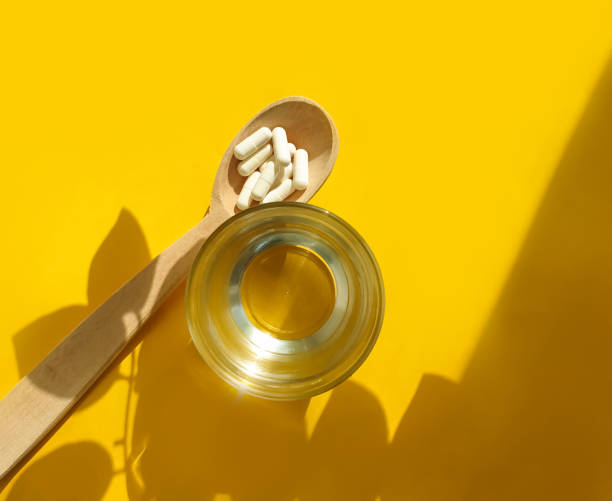 istock wooden spoon, collagen capsules on a colored background 1305660164