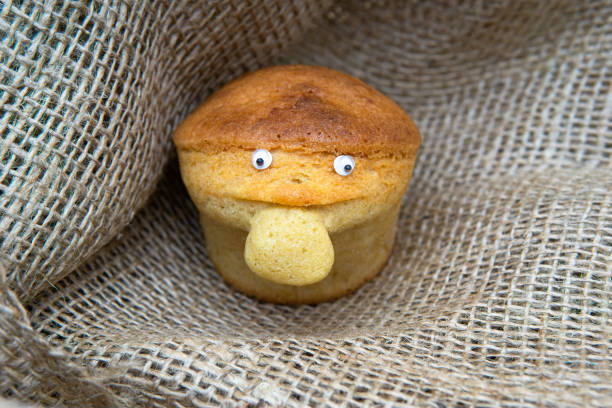 Homemade muffin with a big nose and small eyes on a burlap cloth. Cute food character.
