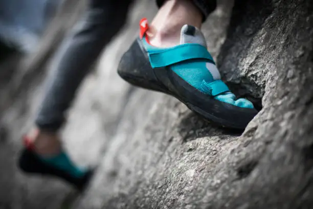 Close up shot o a person climbing while wearing rock climbing shoes.