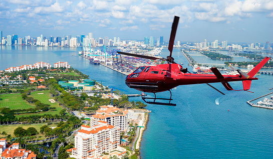 san Francisco, United States – October 08, 2023: A vivid orange helicopter is seen in the sky above a calm body of water, hovering in mid-air