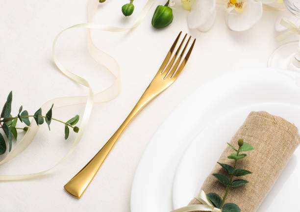 istock Wedding table setting with white crockery, gold cutlery and flowers on a white tablecloth, holiday table setting 1305671408