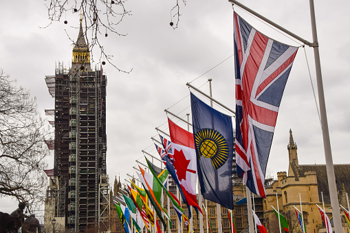 London, United Kingdom - March 6 2021: A view of Big Ben and national flags installed at Parliament Square in London ahead of Commonwealth Day. The annual celebration of the Commonwealth takes place on 8 March 2021, with commemorations set to take place virtually this year in light of the ongoing coronavirus pandemic.