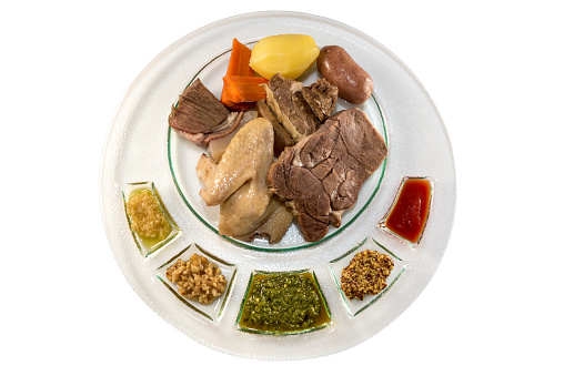 mixed boiled meat, typical Piedmontese Italian dish with sausage, beef and chicken and sauces in plate isolateed on white in top view