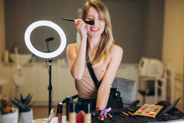 istock The beautiful blonde is laughing and closes one eye with a brush for makeup. Young beautiful woman holding makeup brush near her nose 1305680708