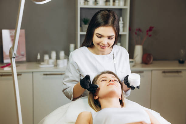 istock Cosmetologist applying cream essence essential vitamins into face to improve client skin. Beauty expert makes beauty treatment for patient. Health, skin care, aethetic medicine concept 1305681630