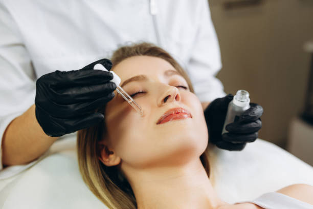istock osmetologist applying serum essence essential vitamins oils water into face to improve client skin. Beauty expert makes beauty treatment for patient. Health, skin care, aethetic medicine concept 1305681636