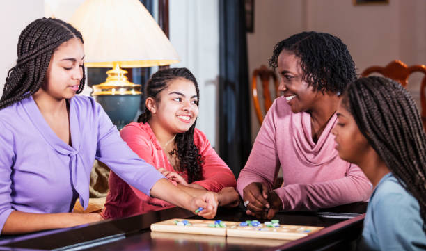 istock Mother and three teenage daughters playing board game 1305684070