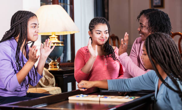 istock Mother and three teenage daughters playing board game 1305684082