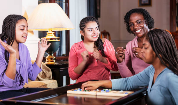 istock Mother and three teenage daughters playing board game 1305684093