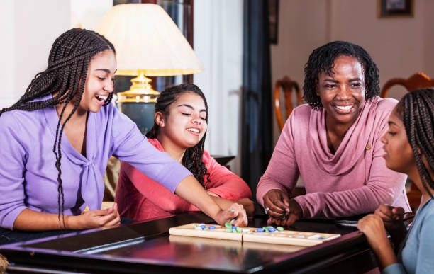 istock Mother and three teenage daughters playing board game 1305684107