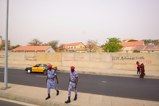 dakar, Senegal - May 21,2012 : Two police officers crossing a buy Dakar street while two mature woman have just emerged from a taxi and look back down the street