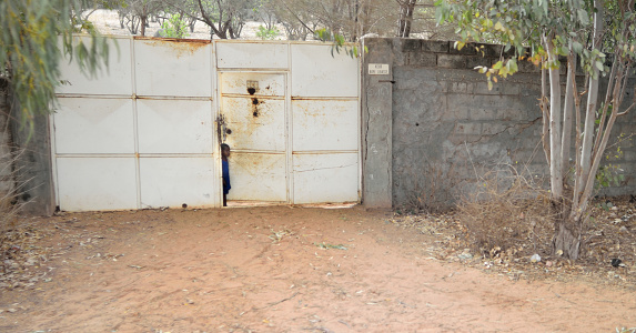 Dakar, Senegal - May 21,2012 : A small pre-school boy peeking out from a gateway into the outside world.