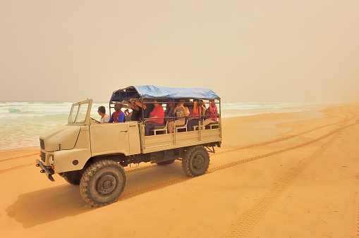 Dakar, Senegal - May 21,2012 : An ATV truck driving a load of tourist along the shore of Lake Retba, Lac Rose, used for salt mining by the local peoples.  Judging by the time of year and sky, there is a sand storm brewing