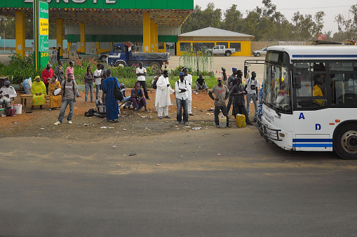 Dakar, Senegal - May 21,2012 : A large group of morning commuters boarding a bus in Dakar in front of a gas station
