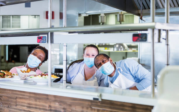 istock Workers in restaurant kitchen, wearing face masks 1305686572