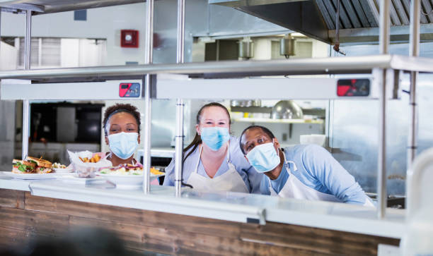 istock Workers in restaurant kitchen, wearing face masks 1305686602