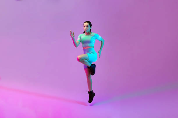 istock Young sportive woman training isolated on gradient studio background in neon light. athletic and graceful. Modern sport, action, motion, youth concept. Beautiful caucasian woman practicing. 1305691828