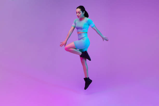 istock Young sportive woman training isolated on gradient studio background in neon light. athletic and graceful. Modern sport, action, motion, youth concept. Beautiful caucasian woman practicing 1305691842
