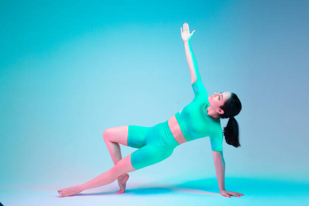 istock Plank. Young sportive woman training isolated on gradient studio background in neon light. athletic and graceful. Modern sport, action, motion, youth concept. Beautiful caucasian woman practicing. 1305691968