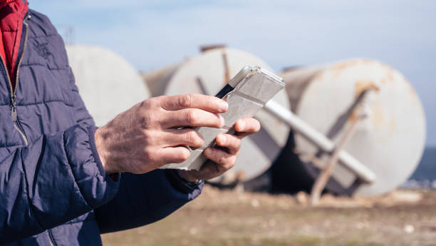 brennstoff- und stromerzeugungssysteme-ölfeld. nahaufnahme der hände mit digitalen tablets in einem erdölkraftwerk bei sonnenuntergang. wartungsingenieur, der während der covid-19-pandemie auf dem feld arbeitet. - storage tank storage compartment fuel and power generation oil industry stock-fotos und bilder