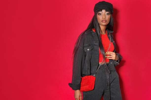 Pretty afroamerican model in styles black jeans clothes on red background.
