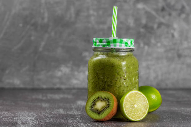 istock Step 5. Jar a mug with ready-made banana, kiwi and spinach smoothie with apple juice. Fresh citrus fruits and kiwis lie next to the jar 1305697210