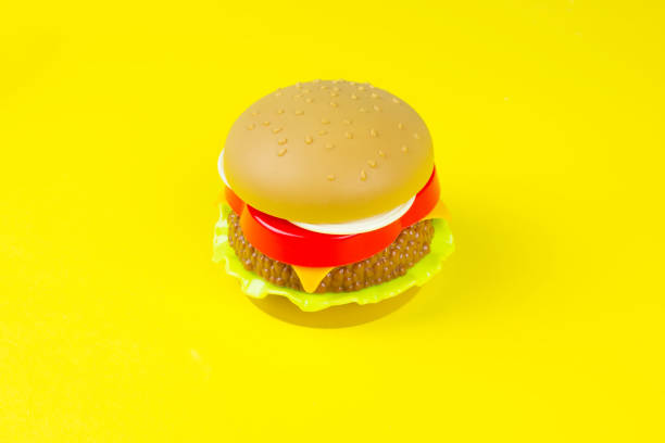 istock Plastic hamburger on a yellow background. Closeup hamburger toy on yellow background. 1305698225