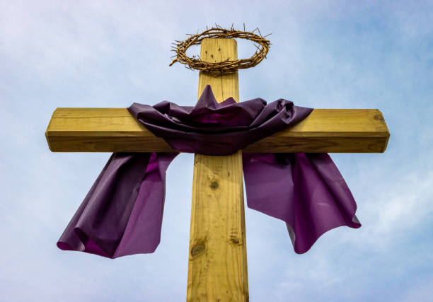Wooden cross with crown of thorns and purple Lent cloth outside on sunny day stock photo