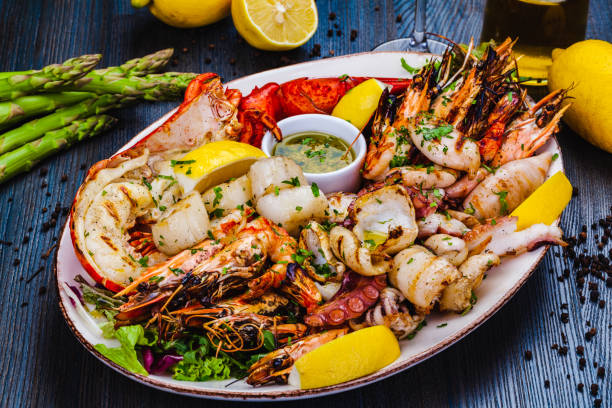 seafood platter. grilled lobster, shrimps, scallops, langoustines, octopus, squid on white plate. - fish plate dishware dinner imagens e fotografias de stock