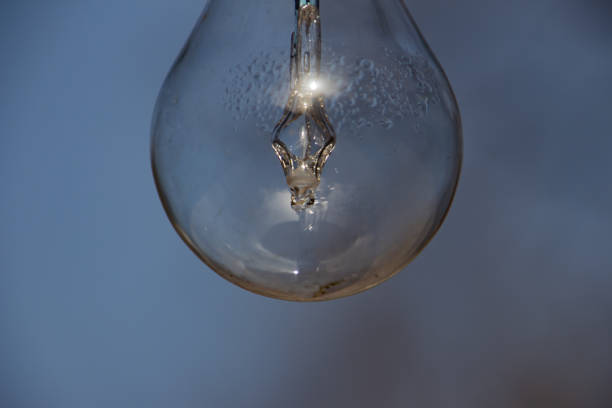 istock Close up of a vintage lightbulb hanging outdoors with condensationvdroplets inside 1305700350