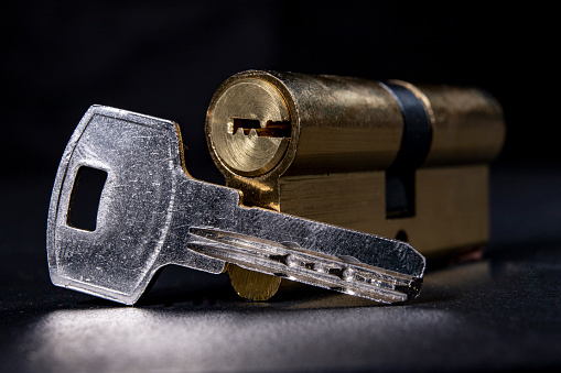 Silver keys and a lock for the front door. Household security system. Dark background.