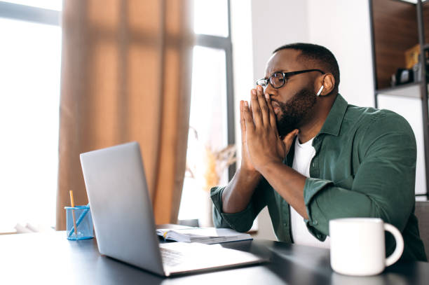 istock Serious focused African American businessman or freelancer working on an important project while sitting at his desk  concentrated looks into a laptop, thinking about work 1305701582