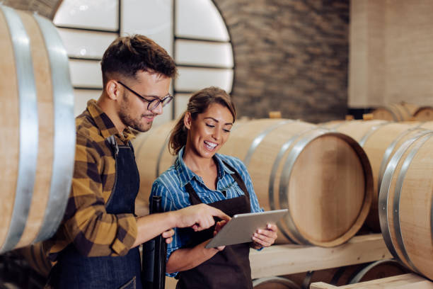 Happy couple of entrepreneurs running the business at their winery Young couple working at their winery on product inspection. man wearing a barrel stock pictures, royalty-free photos & images
