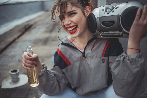 Retro style of a young girl. A recording of an attractive young woman listening to music on the roof of a building with her tape recorder.