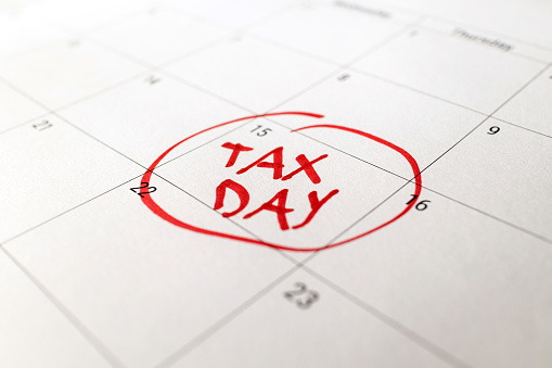 Tax day marked on April 15 calendar with red marker. Deadline for 1040 form return.
