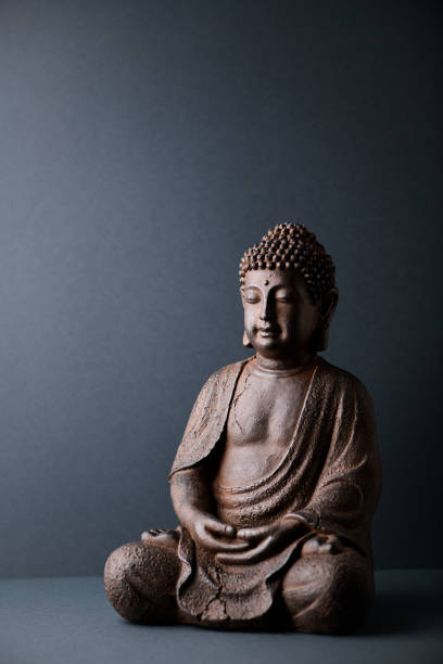 istock Meditating Buddha Statue on paper background. Copy space. 1305707883