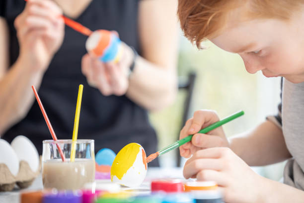 istock Mother and Son Decorating Easter Eggs with Paint at Home 1305709283
