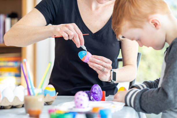 istock Mother and Son Decorating Easter Eggs with Paint at Home 1305709381