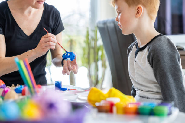istock Mother and Son Decorating Easter Eggs with Paint at Home 1305709590