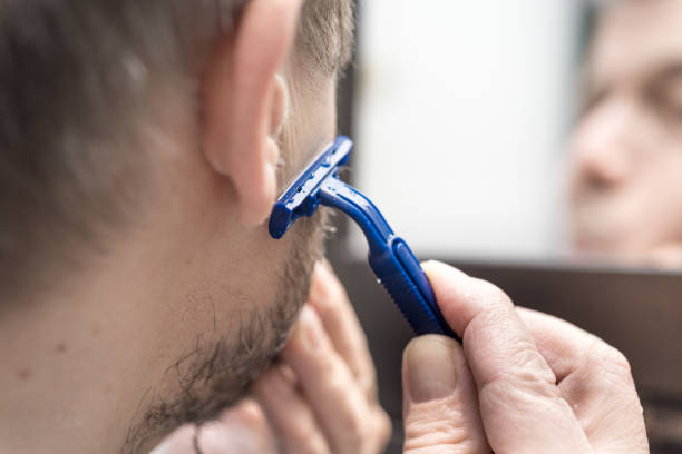 Man Shaving the Beard in front of the Bathroom Mirror