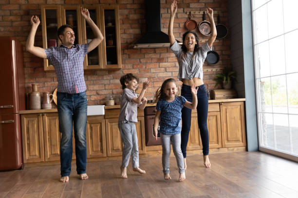 istock Overjoyed mother and father with little kids dancing in kitchen 1305721834