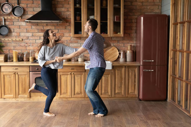istock Overjoyed man and woman holding hands, dancing in modern kitchen 1305721853